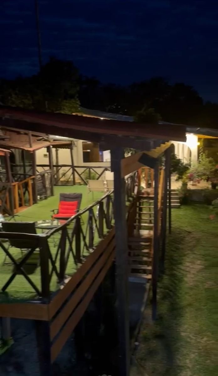 La terraza de la cabaña de noche, con sillas y el jardín iluminado
