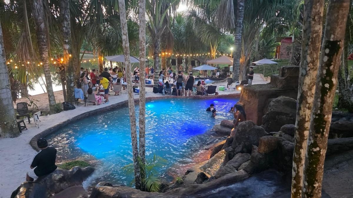 Un evento al atardecer, con luces colgantes y la piscina iluminada